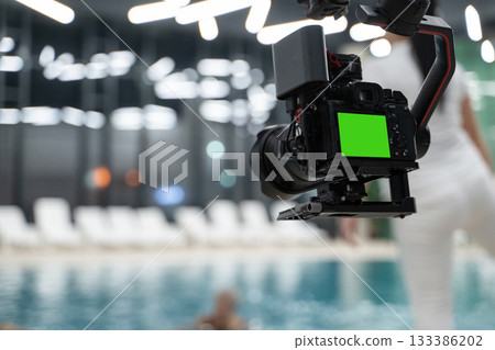 Professional Camera on Gimbal with Green Screen Display Filming Near Pool 133386202