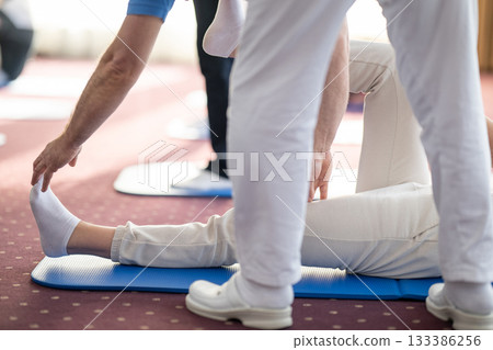 Instructor Helping Woman Stretch During Pilates or Rehabilitation Class Instructor Helping Woman Stretch During Pilates or Rehabilitation Class 133386256