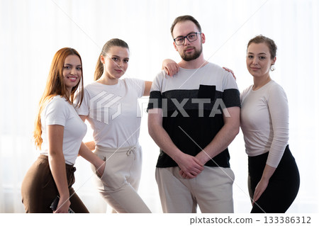 Group of confident young adults standing together in casual outfits, smiling and posing for the camera in a bright indoor setting. Concept of friendship, teamwork, confidence, and positive 133386312