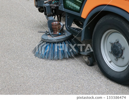 Street sweeper is cleaning the street with a blue brush Street sweeper is cleaning the street with a blue brush 133386474