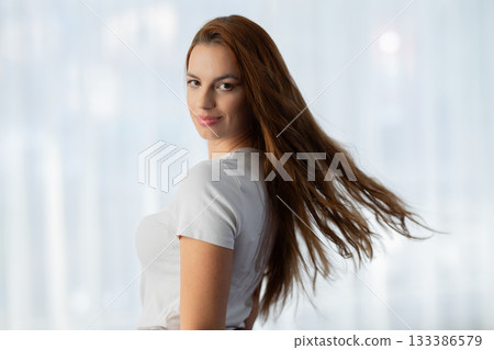 Portrait of a confident young woman with long hair looking at the camera, while people talk in the blurred background. Concept of confidence, individuality, beauty, focus, and empowerment. 133386579