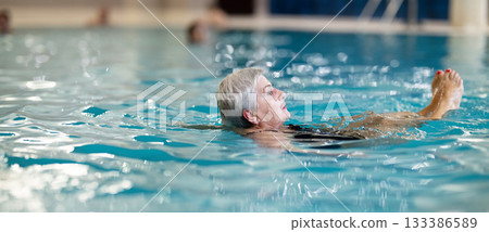 Senior Woman Swimming and Relaxing in Indoor Pool 133386589