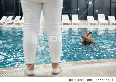 Instructor leading aquatic fitness training for group senior women in a swimming pool. Concept of health, exercise, wellness, water therapy, and active aging lifestyle 133386591