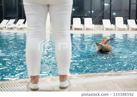 Instructor leading aquatic fitness training for group senior women in a swimming pool. Concept of health, exercise, wellness, water therapy, and active aging lifestyle 133386592
