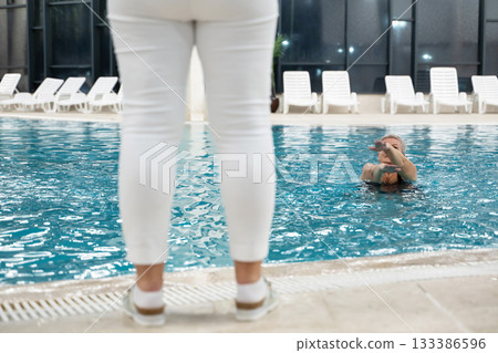Instructor leading aquatic fitness training for group senior women in a swimming pool. Concept of health, exercise, wellness, water therapy, and active aging lifestyle 133386596