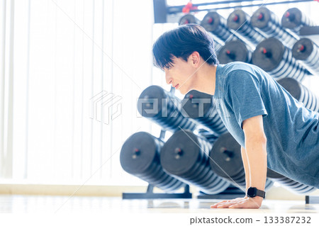 一名年輕男子在健身房做伏地挺身。 133387232