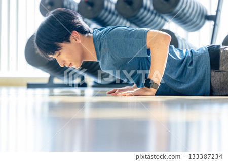 一名年輕男子在健身房做伏地挺身。 一名年輕男子在健身房做伏地挺身。 133387234
