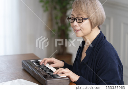 一位老年婦女彈奏鍵盤 一位老年婦女彈奏鍵盤 133387963