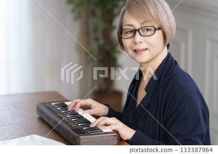 一位老年婦女彈奏鍵盤 一位老年婦女彈奏鍵盤 133387964