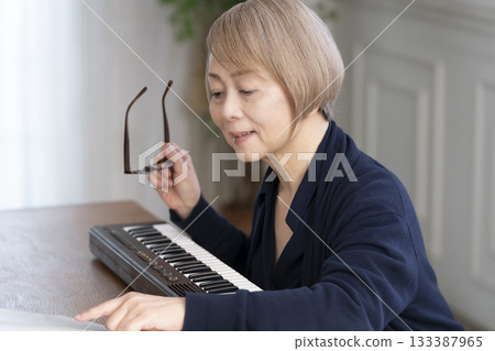 一位老年婦女彈奏鍵盤 一位老年婦女彈奏鍵盤 133387965