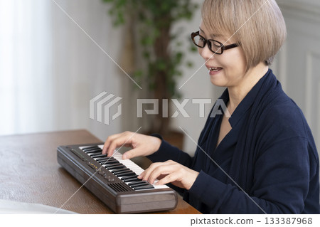 一位老年婦女彈奏鍵盤 一位老年婦女彈奏鍵盤 133387968