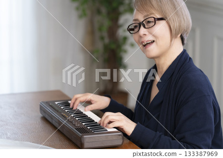 一位老年婦女彈奏鍵盤 一位老年婦女彈奏鍵盤 133387969