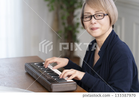 一位老年婦女彈奏鍵盤 一位老年婦女彈奏鍵盤 133387970