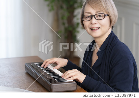 一位老年婦女彈奏鍵盤 一位老年婦女彈奏鍵盤 133387971