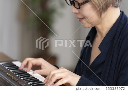 一位老年婦女彈奏鍵盤 一位老年婦女彈奏鍵盤 133387972
