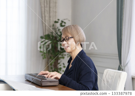 一位老年婦女彈奏鍵盤 一位老年婦女彈奏鍵盤 133387978