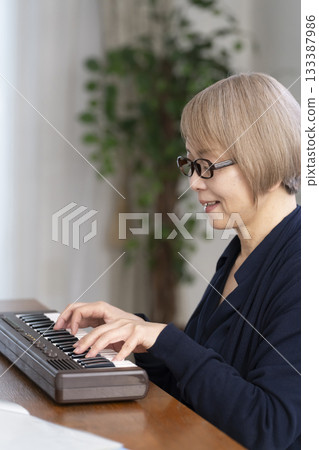 一位老年婦女彈奏鍵盤 一位老年婦女彈奏鍵盤 133387986