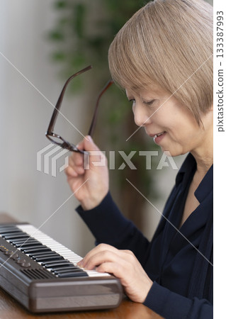 一位老年婦女彈奏鍵盤 一位老年婦女彈奏鍵盤 133387993