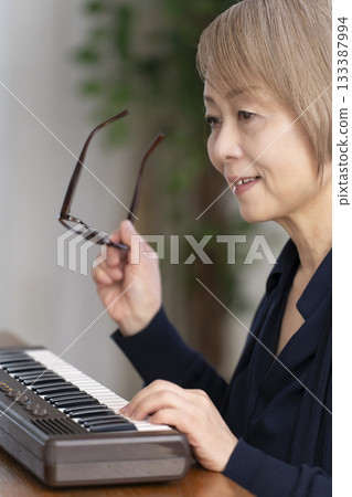 一位老年婦女彈奏鍵盤 一位老年婦女彈奏鍵盤 133387994