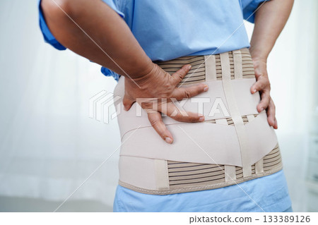 Asian senior pain back wearing elastic support belt with walker. Asian senior pain back wearing elastic support belt with walker. 133389126
