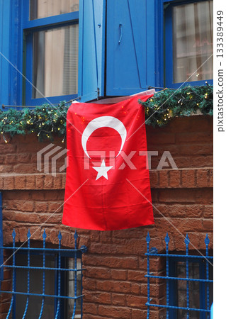 Turkish flag displayed on blue window in a brick building 133389449
