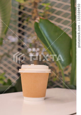 Warm coffee cup on a table near tropical plants 133389450