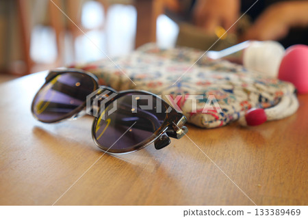 Stylish sunglasses on a wooden table in a cafe setting Stylish sunglasses on a wooden table in a cafe setting 133389469