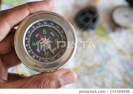 Holding a compass over a detailed map for navigation 133389496