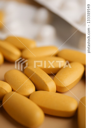 Bright yellow tablets scattered on a surface with packaging Bright yellow tablets scattered on a surface with packaging 133389549