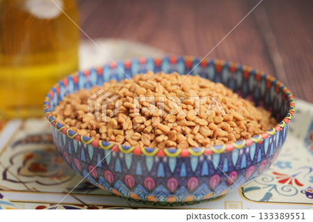 Colorful bowl of healthy fenugreek seeds on wood Colorful bowl of healthy fenugreek seeds on wood 133389551