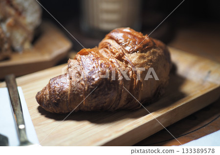 Freshly baked croissant on wooden board at cafe Freshly baked croissant on wooden board at cafe 133389578