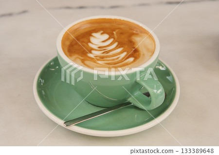 Warm coffee cup with latte art on a green saucer Warm coffee cup with latte art on a green saucer 133389648