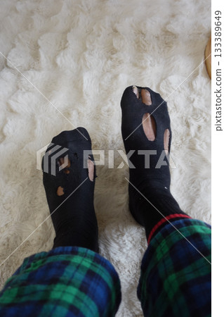 Worn socks with holes on a cozy carpeted floor Worn socks with holes on a cozy carpeted floor 133389649