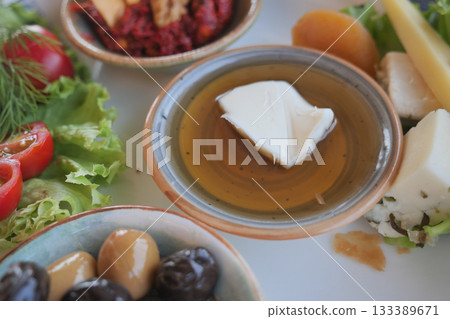 Delicious spread featuring olives, feta cheese, herbs and honey on a plate. 133389671