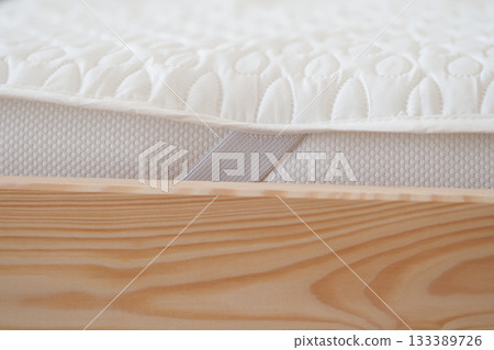 Soft mattress on wooden bed frame showcasing cozy design 133389726