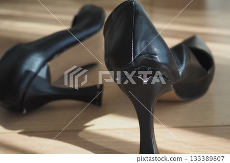 High heel shoes with visible damage on wooden floor High heel shoes with visible damage on wooden floor 133389807