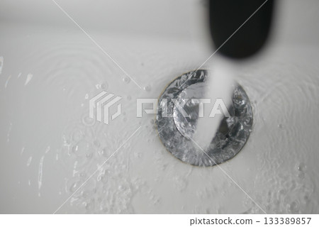 Flowing water from faucet into a white sink 133389857
