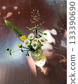 A beautiful flower arrangement in a glass vase casting a shadow on a wood surface 133390690