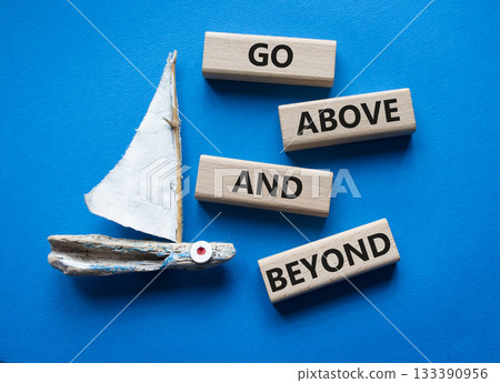 Go above and beyond symbol. Wooden blocks with words Go above and beyond. Beautiful blue background with boat. Business concept. Copy space. 133390956