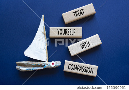 Treat yourself with compassion symbol. Concept words Treat yourself with compassion on wooden blocks with boat. Beautiful deep blue background. Medicine concept. Copy space. 133390961