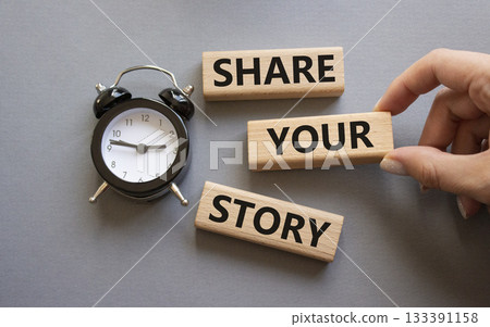 Share your story symbol. Wooden blocks with words Share your story. Businessman hand. Beautiful grey background with alarm clock. Business and Share your story concept. Copy space. 133391158