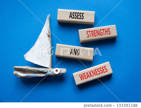 Strengths and Weaknesses symbol. Wooden blocks with words Assess Strengths and Weaknesses. Beautiful blue background with boat. Business and Assess Strengths and Weaknesses concept. Copy space. 133391186