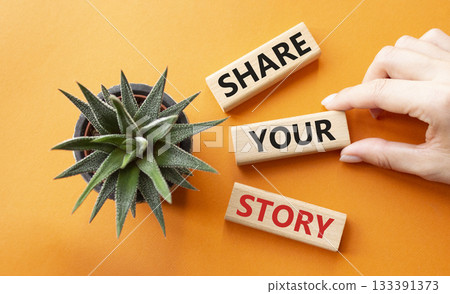 Share your story symbol. Wooden blocks with words Share your story. Beautiful orange background with succulent plant. Businessman hand. Business and Share your story concept. Copy space. Share your story symbol. Wooden blocks with words Share your story. Beautiful orange background with succulent plant. Businessman hand. Business and Share your story concept. Copy space. 133391373