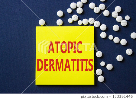 Atopic Dermatitis symbol. Concept word Atopic Dermatitis on yellow note. Beautiful deep blue background with pills. Medicine and Atopic Dermatitis concept. Copy space Atopic Dermatitis symbol. Concept word Atopic Dermatitis on yellow note. Beautiful deep blue background with pills. Medicine and Atopic Dermatitis concept. Copy space 133391446