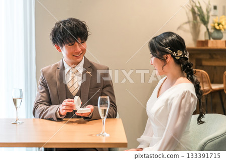 A man proposing at a restaurant and a woman receiving a ring 133391715
