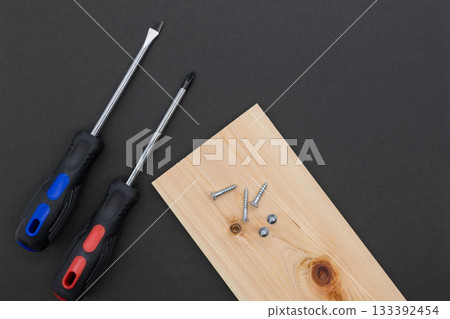 Screwdriver, wood, and screws on a black background 133392454