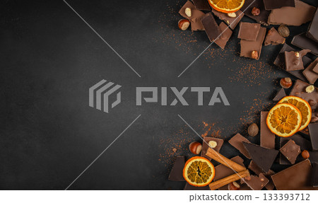 Assorted chocolate pieces with dried orange slices, nuts and cinnamon on dark background with copy space 133393712