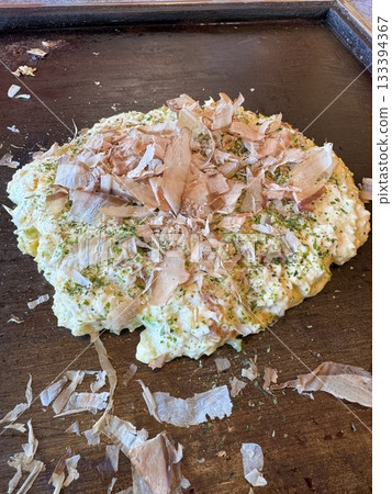 The cooking process of okonomiyaki on a hot plate 133394367