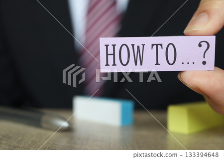 Businessman with sticky note showing HOW TO. Businessman with sticky note showing HOW TO. 133394648