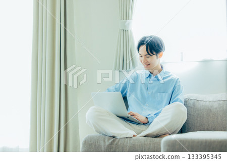 Young man using a computer in the living room 133395345